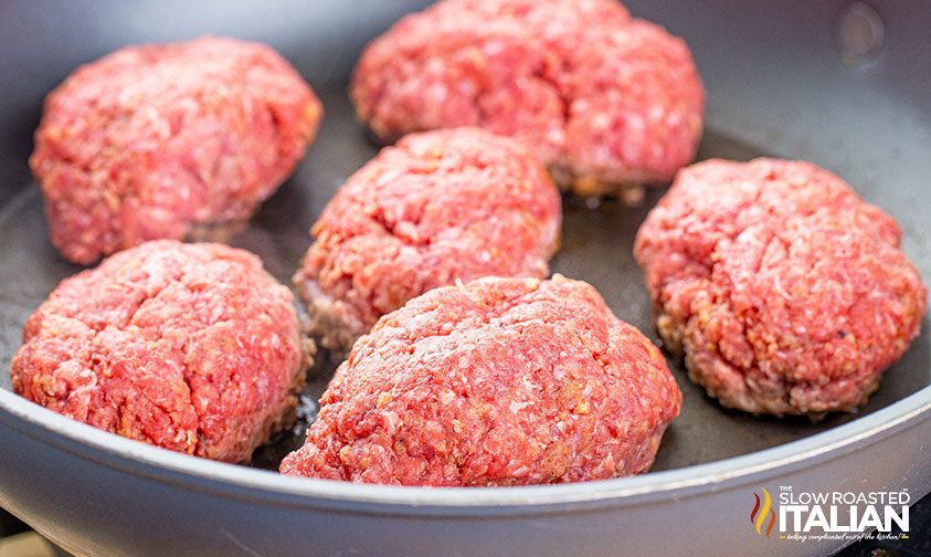 thick patties of ground beef cooking in skillet
