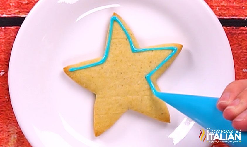 outlining star cookie with blue icing