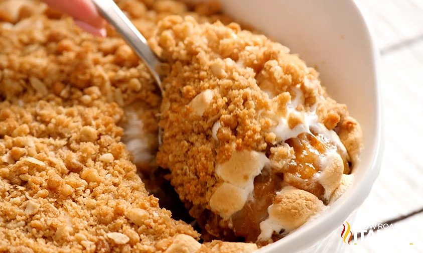 scooping sweet potato casserole with marshmallows from baking dish