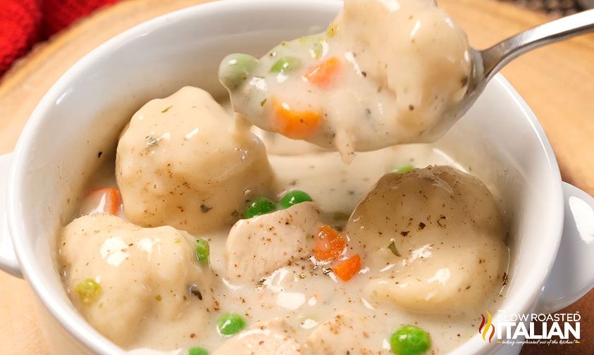 spoonful of creamy chicken and dumplings over white bowl