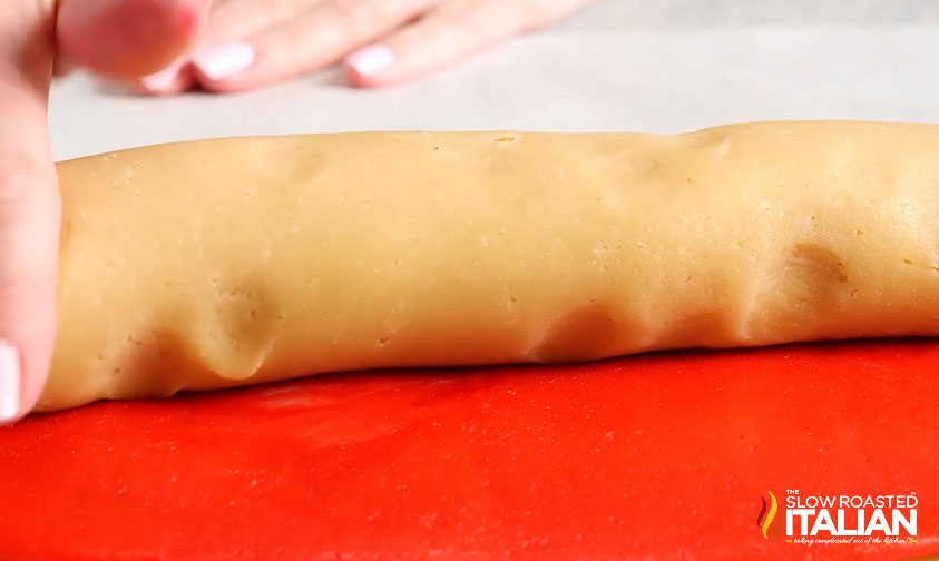 rolling up sheets of red and white cookie dough, close up