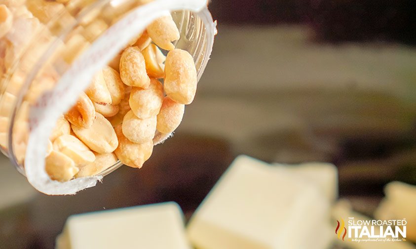 peanuts being poured into pot with vanilla almond bark chunks