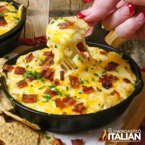 dipping chip into spicy cheese and bacon dip