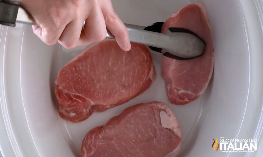 placing boneless pork chops into slow cooker