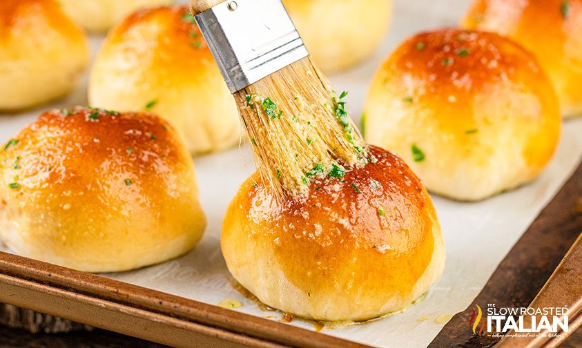 brushing butter on top of dinner rolls