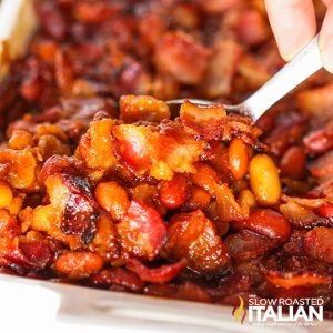 woman's hand holding a spoonful of oven baked beans