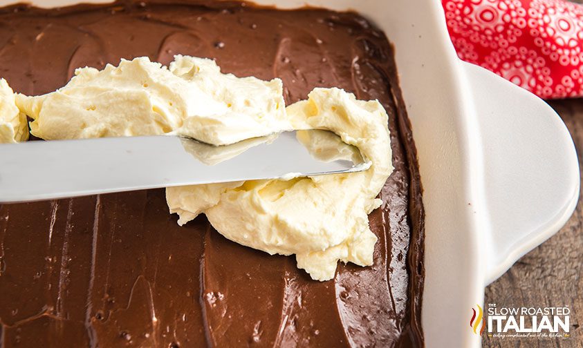 spreading whipped cream onto chocolate pudding