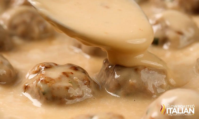 swedish meatball sauce being spooned over the meatballs