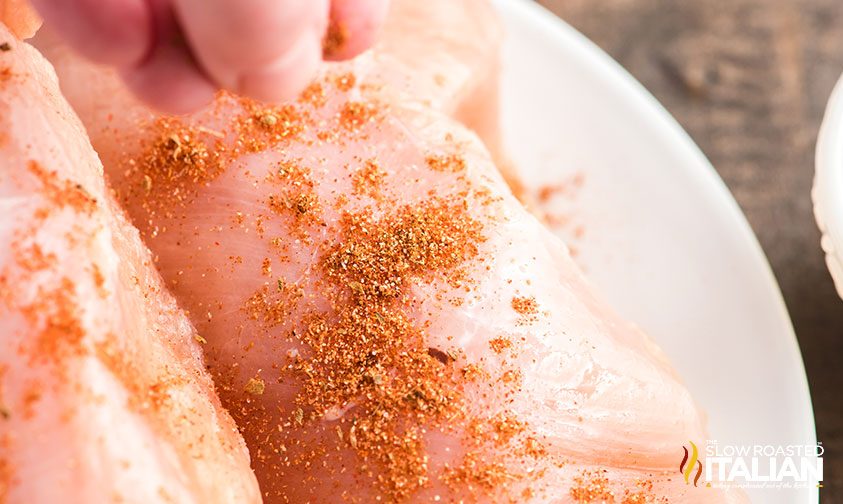 sprinkling seasoning on chicken