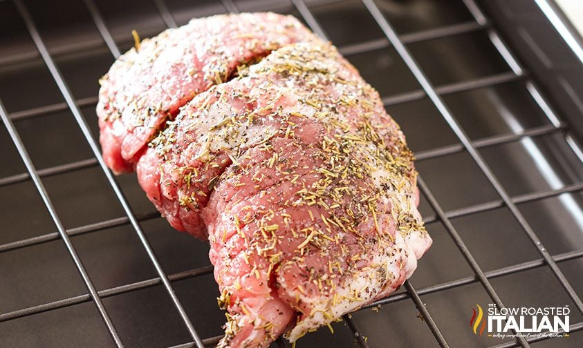 uncooked boneless pork roast on metal roasting rack