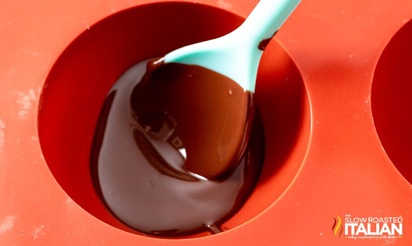 using a spoon to spread chocolate in the mold