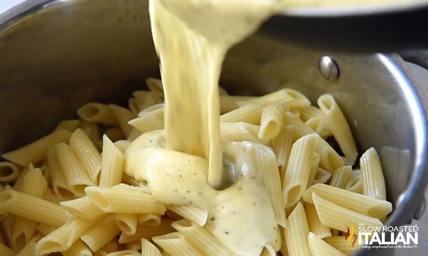 pouring cheese sauce into pasta