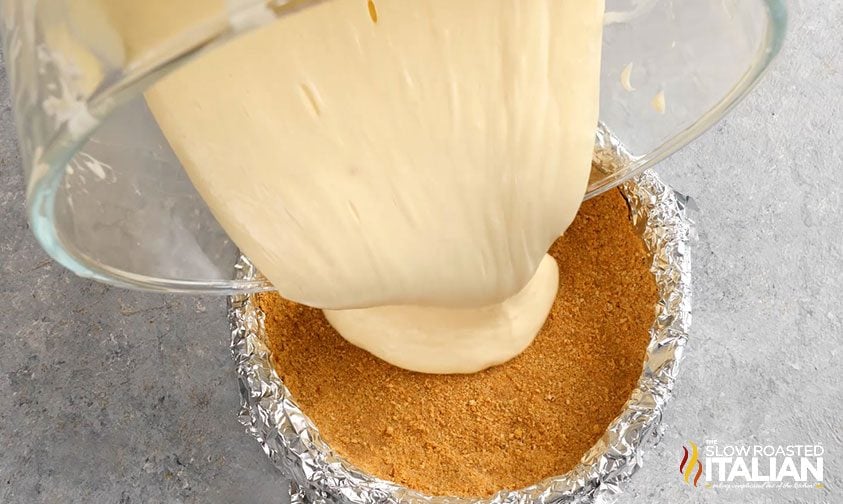 pouring cheesecake mixture into crust