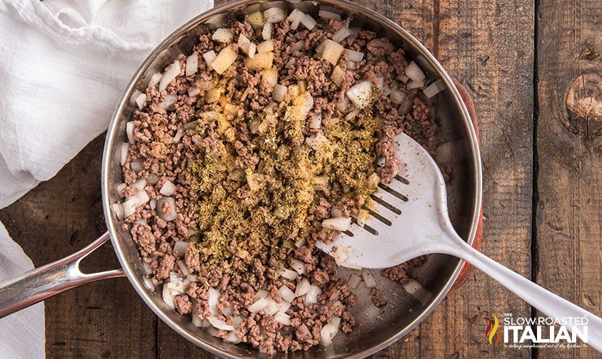 stirring hamburger casserole in a skillet