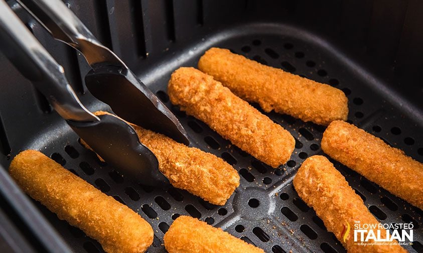 tongs picking up air fried Mozzarella sticks