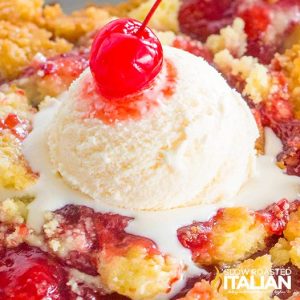 Closeup of cherry dump cake with a scoop of vanilla ice cream and a cherry on top