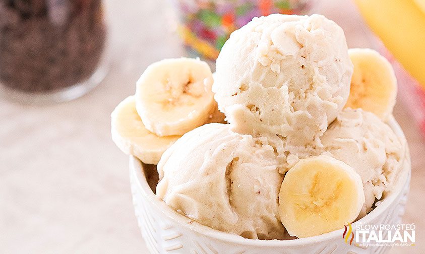 one ingredient nice cream scooped in white bowl with fresh bananas
