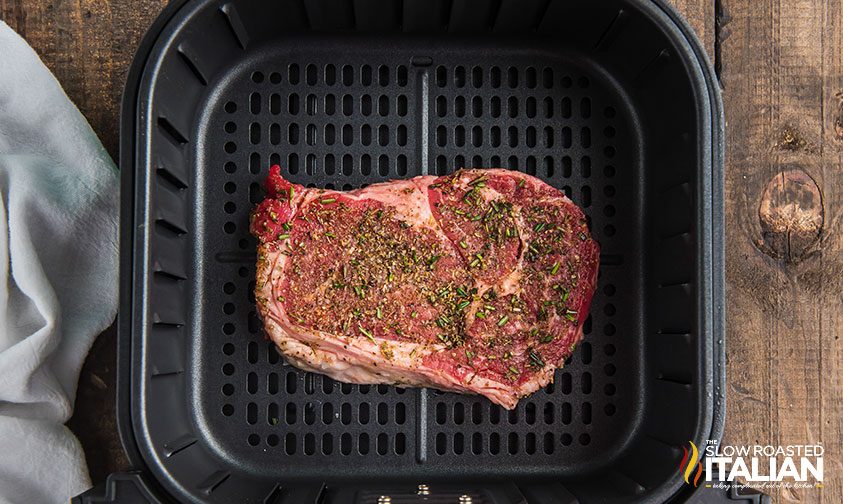 steak with seasoning in air fryer basket