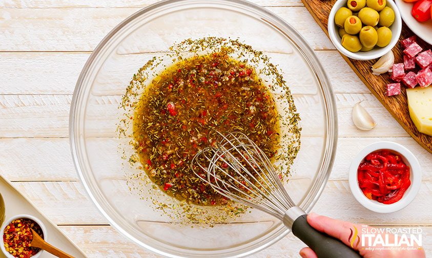 whisking antipasto salad dressing in glass bowl