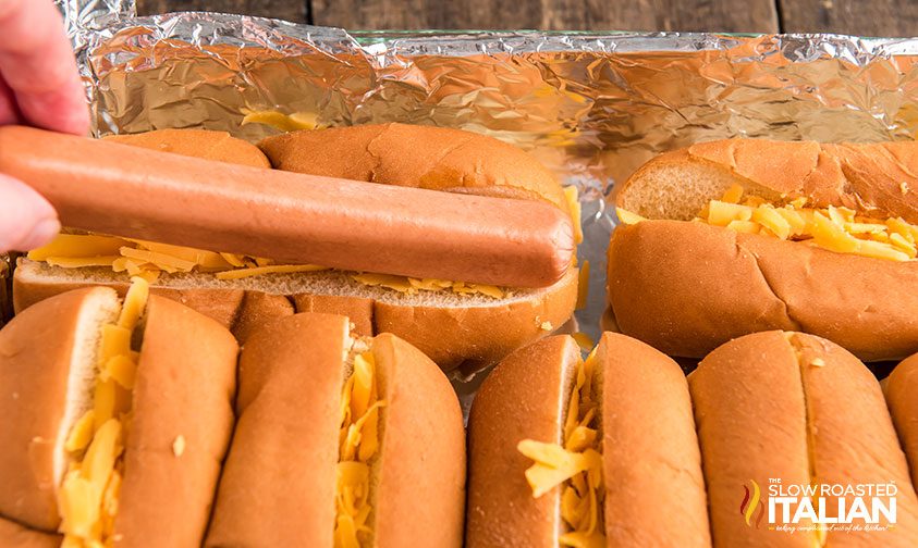 woman's hand assembling chili cheese dog