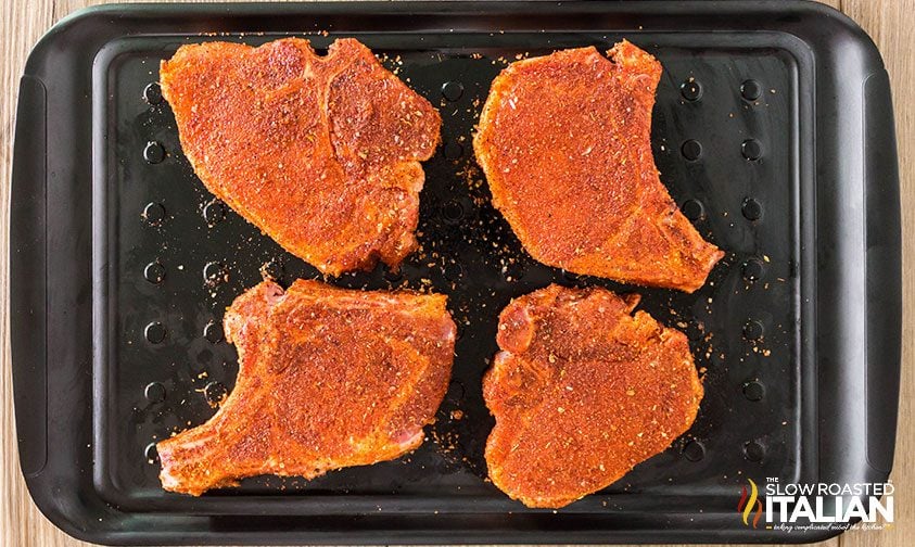 seasoned pork chops on a marinating tray