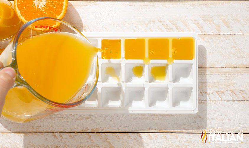 pouring orange juice into ice cube trays