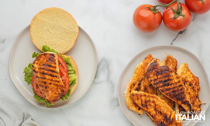 plate of grilled chicken breasts and and open spicy chicken sandwich
