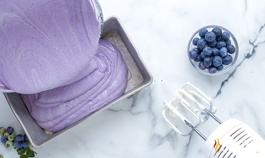 pouring blueberry ice cream into pan to freeze