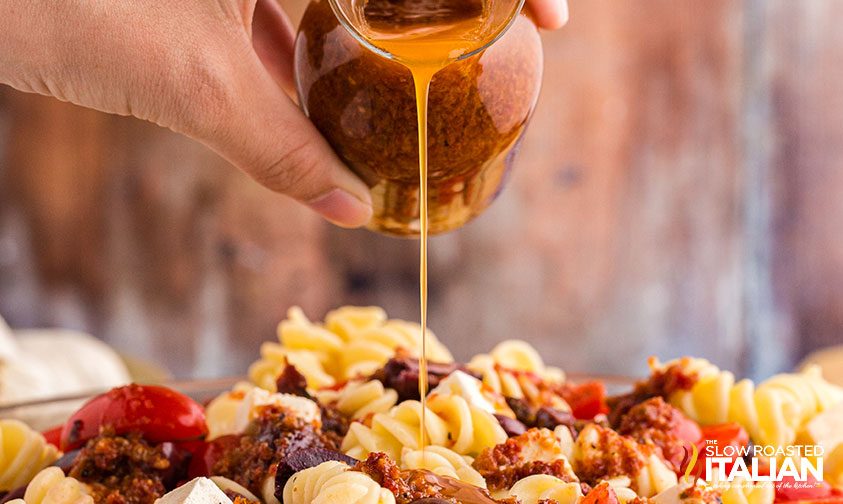 pouring dressing over feta pasta salad