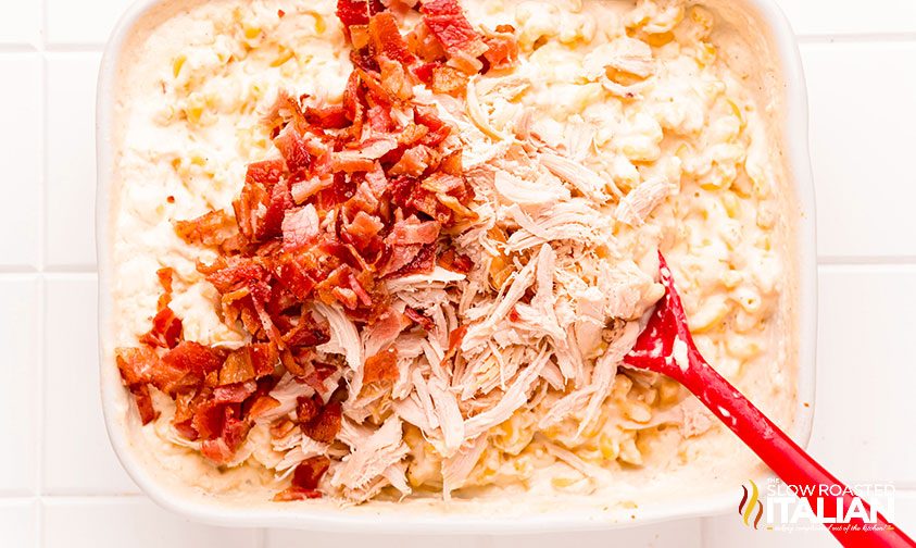 mixing pasta with chopped chicken and bacon pieces
