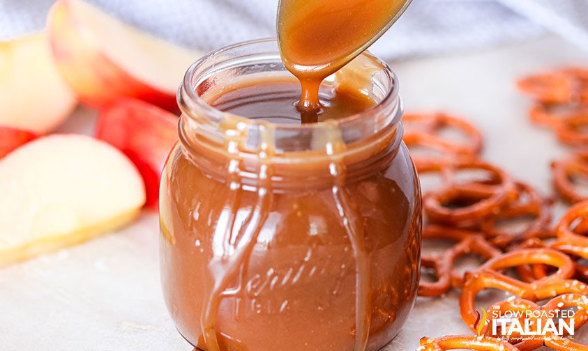 homemade caramel sauce drizzing off a spoon into a jar