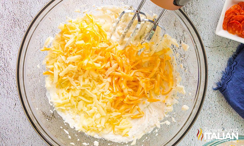 blending shredded cheese and cream cheese in mixing bowl