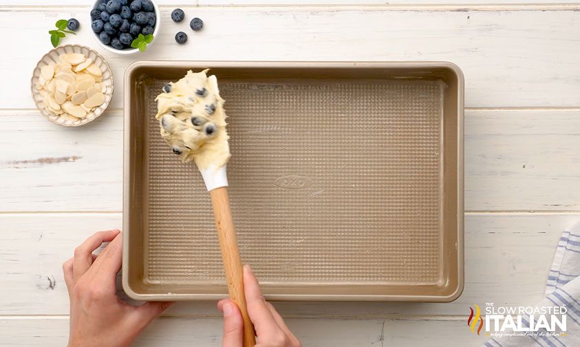 scooping blueberry breakfast cake batter onto pan