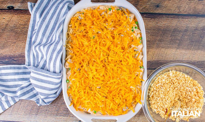 unbaked casserole with shredded cheddar cheese on top