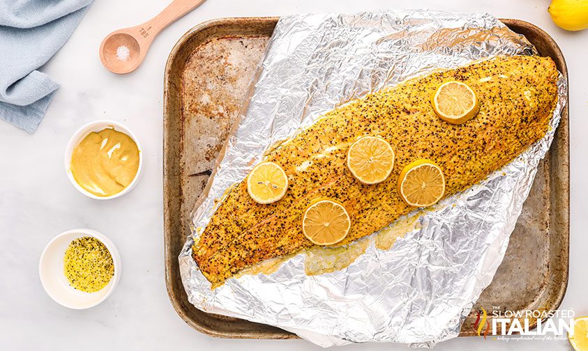 whole salmon filet topped with lemon slices and seasoning