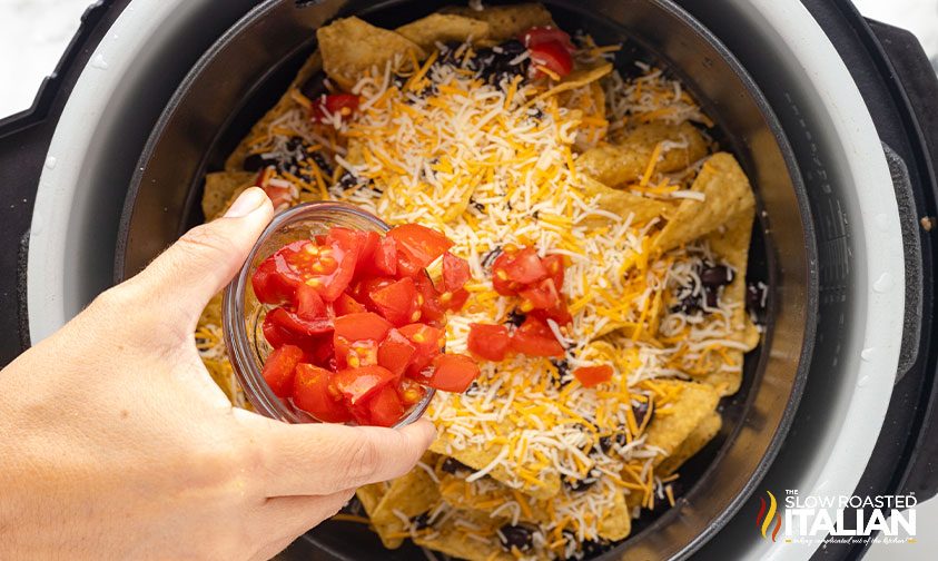 adding diced tomato to corn chips in air fryer