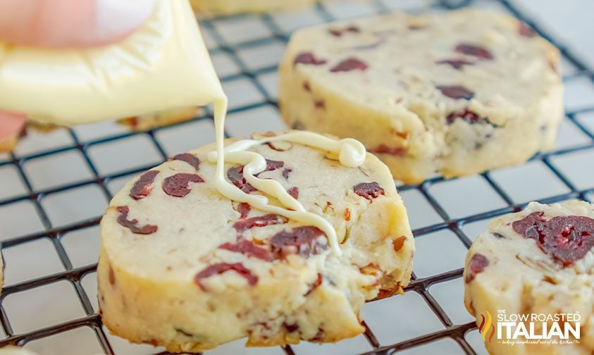 drizzling white chocolate onto cranberry cookies