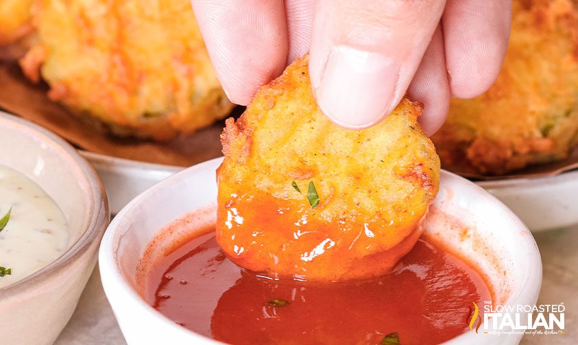 dunking deep fried pickles in hot sauce