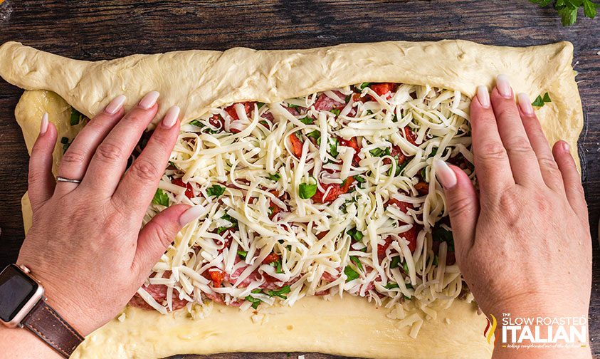 italian stromboli rolled out with fillings on dough