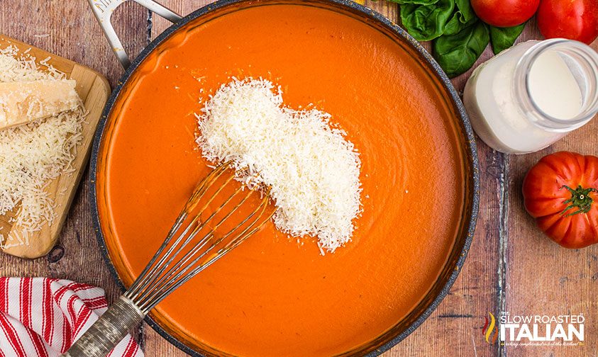 whisking parmesan cheese into vodka cream sauce