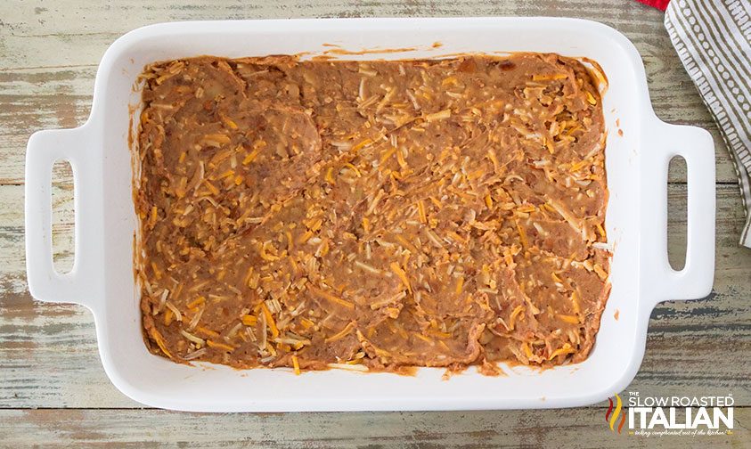 layer of refried beans in white dish