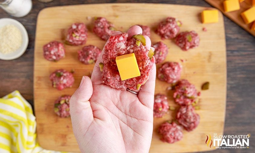 stuffing cube of yellow cheese inside ground beef mixture