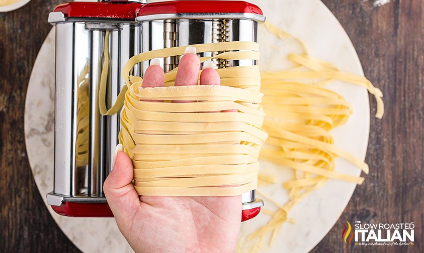 running homemade pasta dough through pasta sheet roller