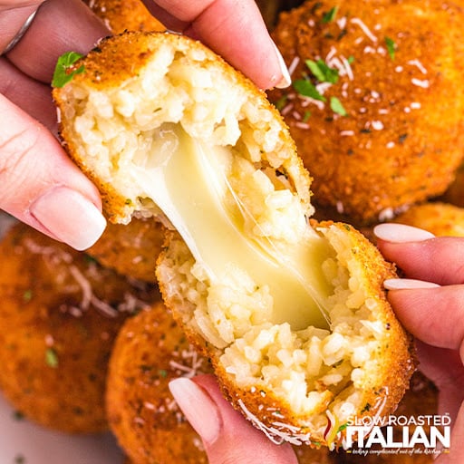 woman's hands pulling apart cheesy fried italian appetizer