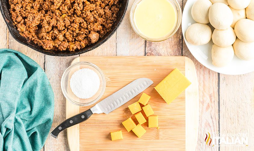 slicing cubes of yellow cheese on cutting board