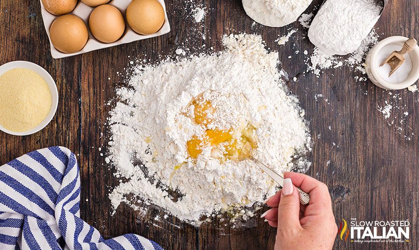 mixing egg into mound of flour on counter top