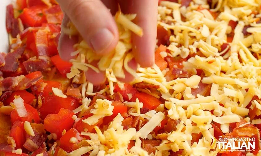 adding shredded cheese to top of mexican breakfast lasagna