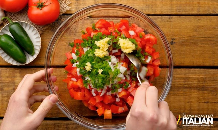 stirring salsa ingredients together in glass bowl