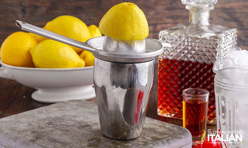 squeezing lemons into cocktail shaker for amaretto sour recipe