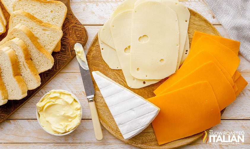 slices of swiss, brie and cheddar cheese on cutting board